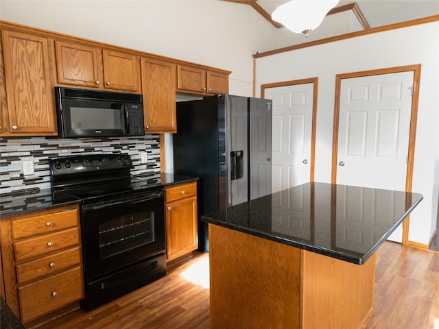 kitchen with backsplash, light wood-type flooring, a kitchen island, and black appliances