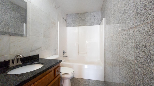 full bathroom with vanity, tub / shower combination, tile walls, and toilet