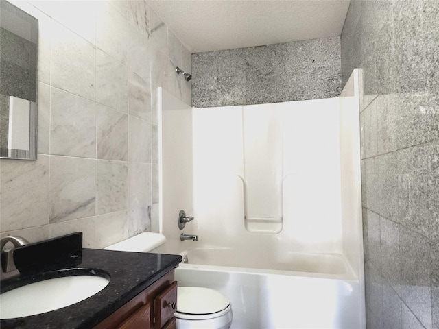 full bathroom with tile walls, vanity,  shower combination, toilet, and a textured ceiling