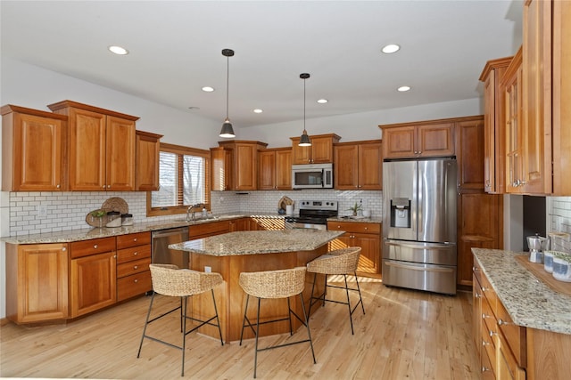 kitchen with stainless steel appliances, a kitchen bar, a center island, and light stone countertops