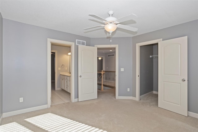 unfurnished bedroom with ceiling fan, connected bathroom, a spacious closet, light colored carpet, and a closet