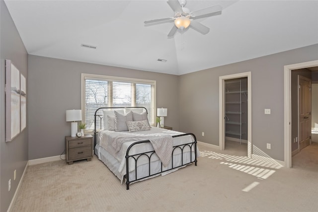 carpeted bedroom with ceiling fan, vaulted ceiling, ensuite bathroom, a walk in closet, and a closet