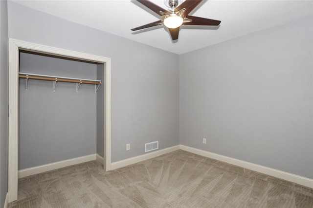 unfurnished bedroom featuring light colored carpet, a closet, and ceiling fan