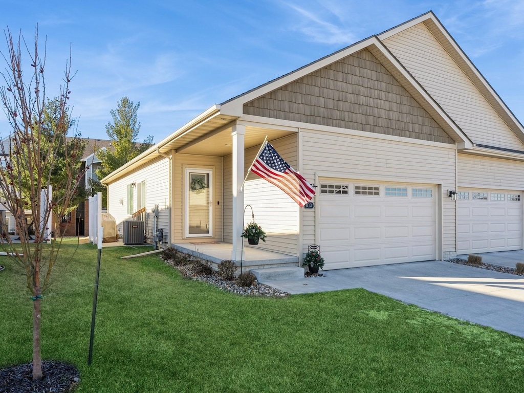 view of front facade featuring a garage, central AC, and a front yard