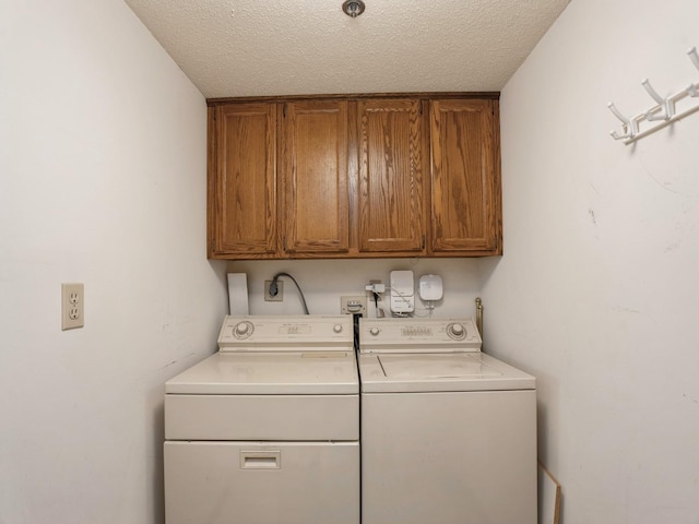 laundry area featuring cabinets, washer and dryer, and a textured ceiling