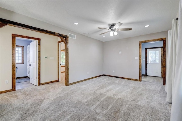 carpeted empty room featuring ceiling fan, a healthy amount of sunlight, and a textured ceiling