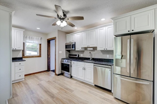 kitchen featuring sink, a textured ceiling, stainless steel appliances, light hardwood / wood-style floors, and white cabinets