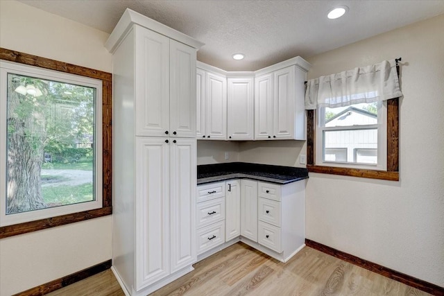 kitchen featuring built in desk, a textured ceiling, white cabinets, and light hardwood / wood-style floors