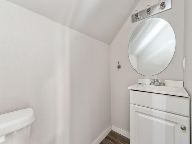 bathroom featuring lofted ceiling, wood-type flooring, toilet, and vanity