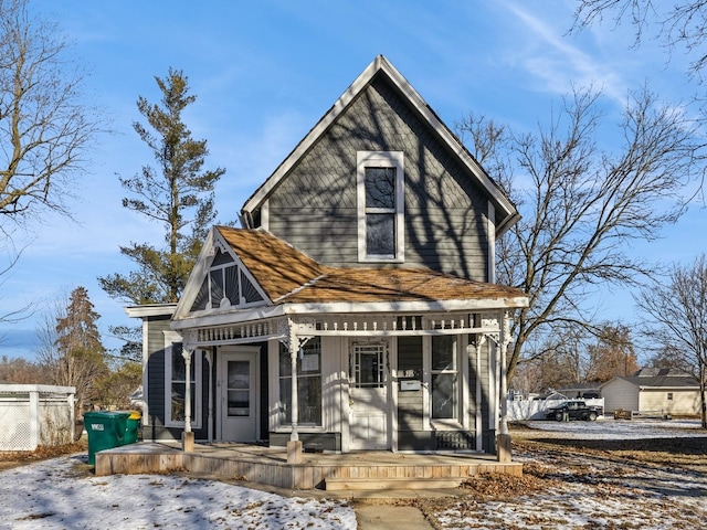 snow covered back of property featuring covered porch