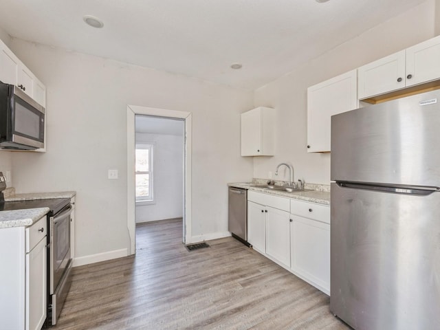 kitchen with stainless steel appliances, sink, light hardwood / wood-style flooring, and white cabinets