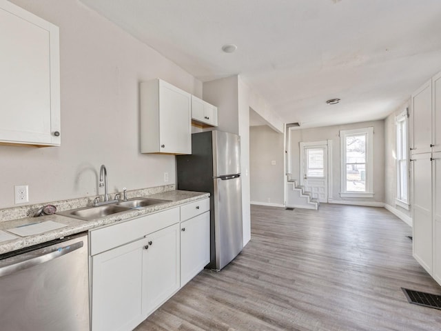 kitchen featuring sink, stainless steel appliances, white cabinets, and light wood-type flooring