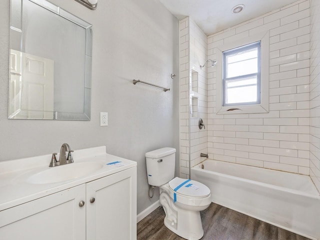 full bathroom with hardwood / wood-style flooring, tiled shower / bath, vanity, and toilet