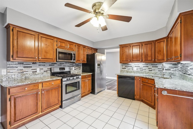 kitchen featuring stainless steel appliances, brown cabinets, a sink, and backsplash