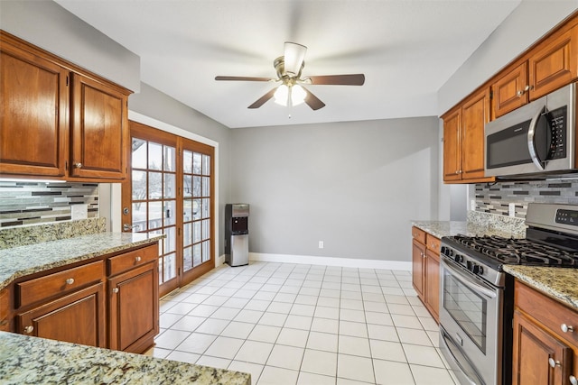 kitchen featuring light stone counters, stainless steel appliances, decorative backsplash, and light tile patterned floors