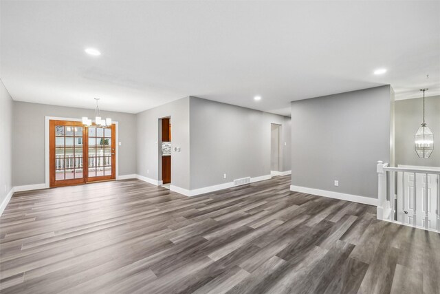 empty room with an inviting chandelier and dark hardwood / wood-style flooring