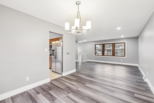 unfurnished dining area featuring an inviting chandelier and light hardwood / wood-style flooring