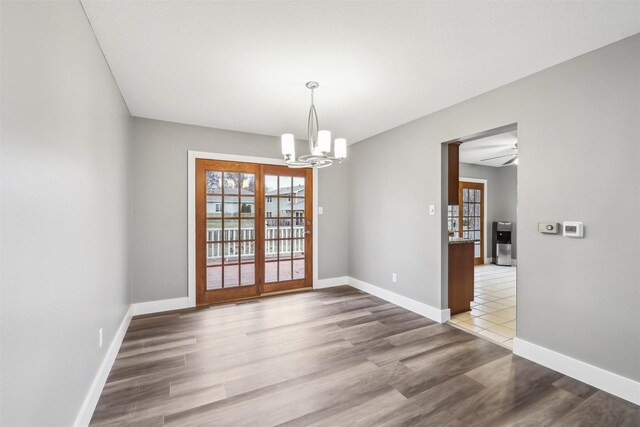 unfurnished dining area with hardwood / wood-style floors, a chandelier, and french doors