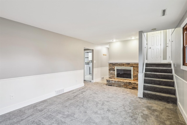 unfurnished living room featuring carpet flooring and a brick fireplace