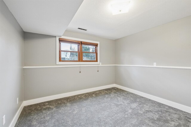 carpeted empty room featuring a textured ceiling