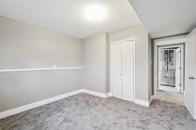 unfurnished bedroom featuring light carpet, a textured ceiling, and a closet