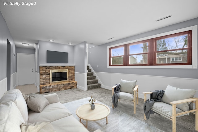 living room with a fireplace, visible vents, carpet flooring, baseboards, and stairs