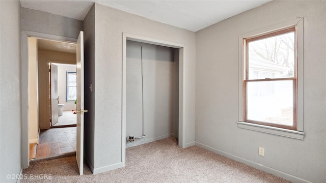 unfurnished bedroom with multiple windows, light colored carpet, and a closet