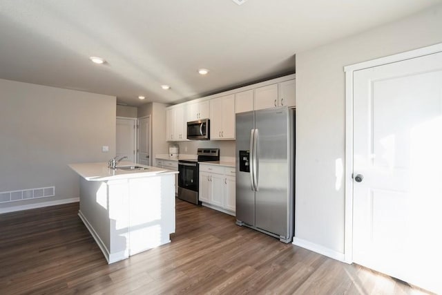 kitchen featuring appliances with stainless steel finishes, white cabinetry, an island with sink, sink, and dark wood-type flooring