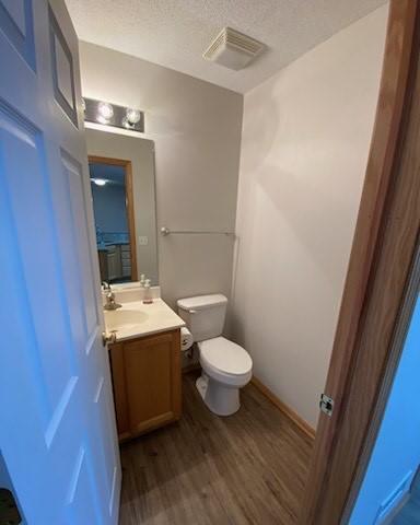 bathroom featuring vanity, hardwood / wood-style floors, a textured ceiling, and toilet