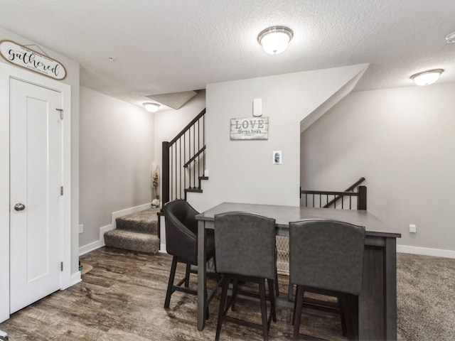 dining room featuring dark wood-type flooring and a textured ceiling