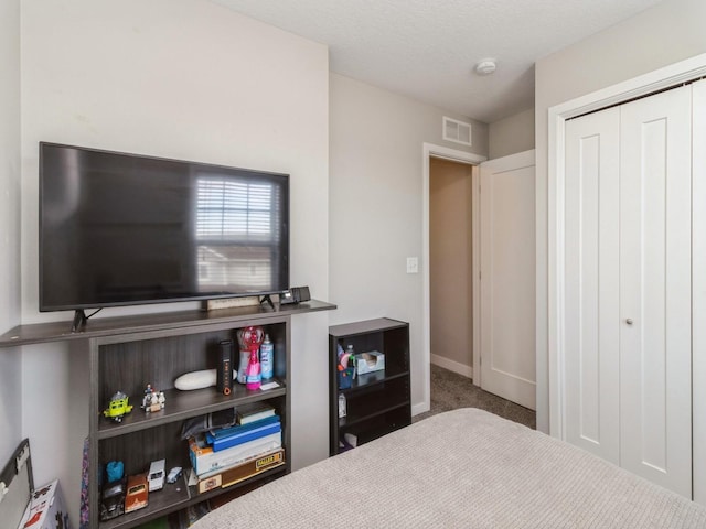 carpeted bedroom featuring a textured ceiling and a closet