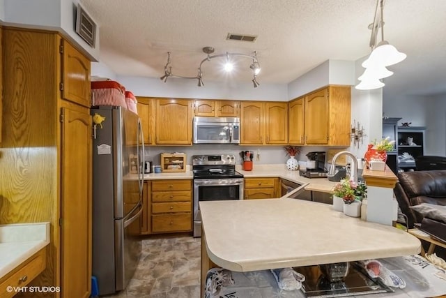 kitchen with sink, a textured ceiling, kitchen peninsula, pendant lighting, and stainless steel appliances