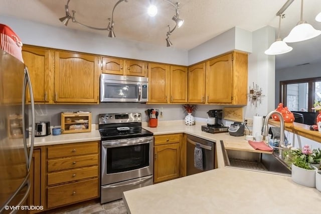 kitchen featuring stainless steel appliances, sink, pendant lighting, and kitchen peninsula