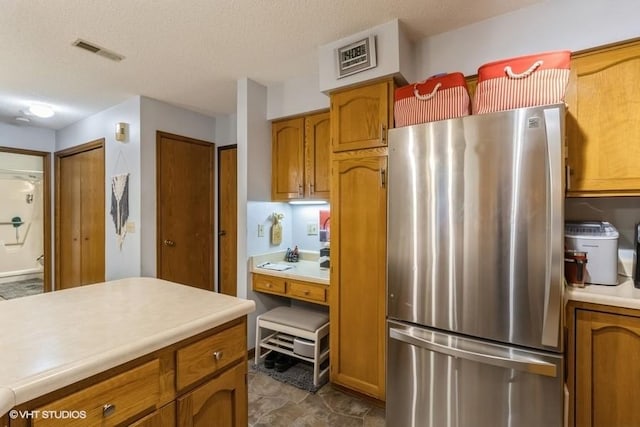 kitchen featuring stainless steel fridge and a textured ceiling