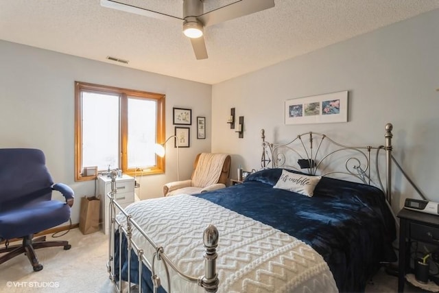 carpeted bedroom with ceiling fan and a textured ceiling