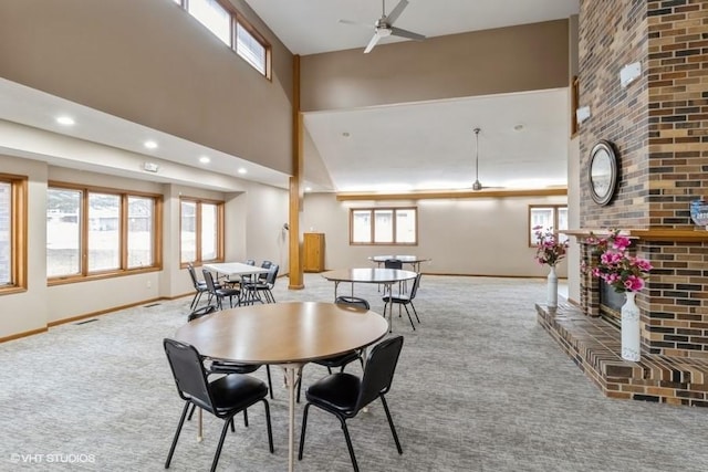 dining room featuring a high ceiling, plenty of natural light, light colored carpet, and a fireplace