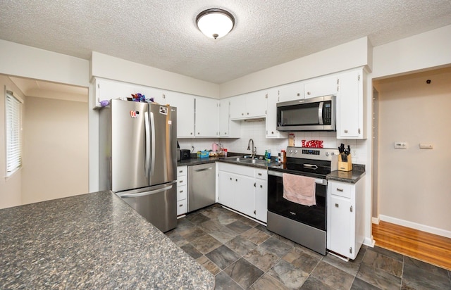 kitchen featuring sink, white cabinetry, a textured ceiling, appliances with stainless steel finishes, and decorative backsplash