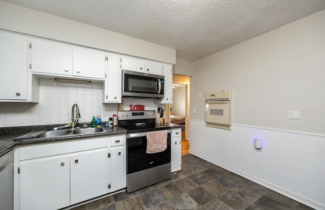 kitchen featuring sink, a textured ceiling, stainless steel appliances, decorative backsplash, and white cabinets