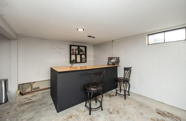 bar with butcher block countertops and concrete floors