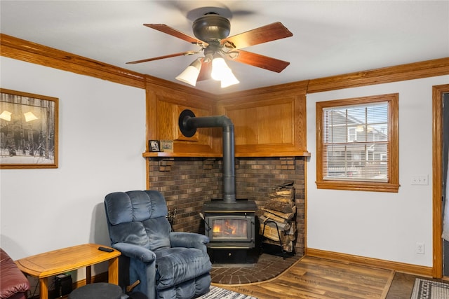 sitting room with crown molding, dark hardwood / wood-style floors, ceiling fan, and a wood stove