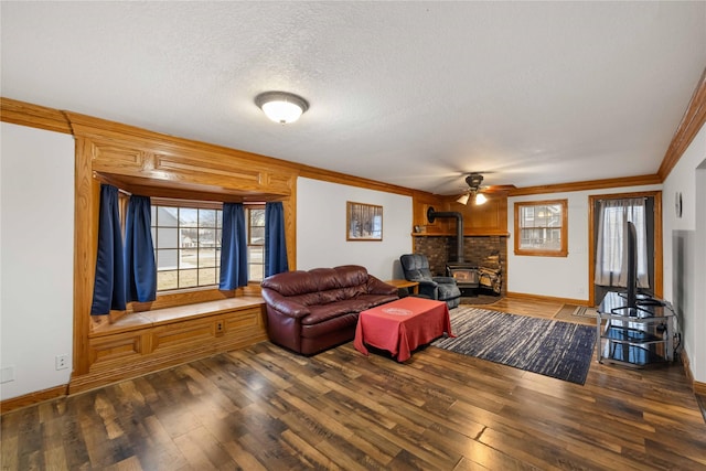 living room with dark wood-type flooring, ornamental molding, a textured ceiling, and a wood stove