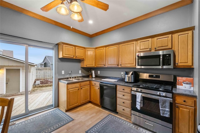 kitchen with sink, ceiling fan, appliances with stainless steel finishes, light hardwood / wood-style floors, and vaulted ceiling