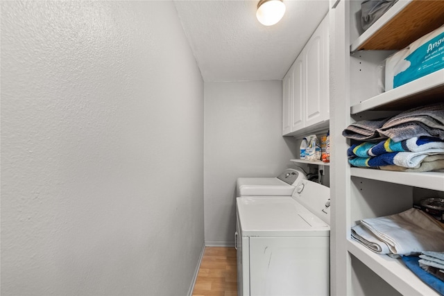 laundry room with separate washer and dryer, cabinets, a textured ceiling, and light wood-type flooring