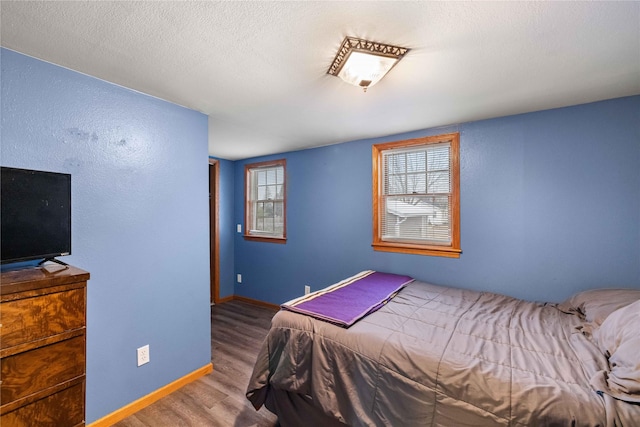 bedroom featuring wood-type flooring, multiple windows, and a textured ceiling