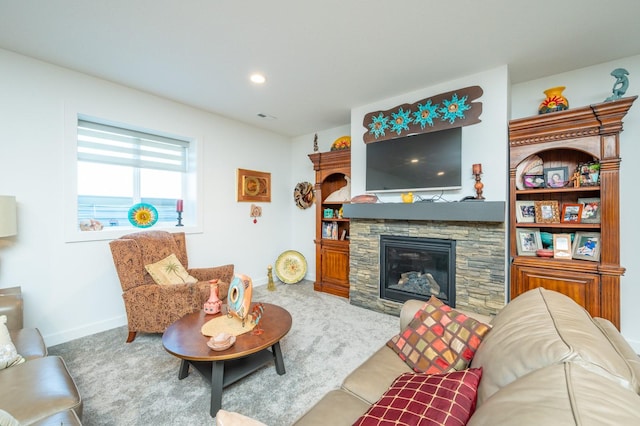 carpeted living room featuring a stone fireplace