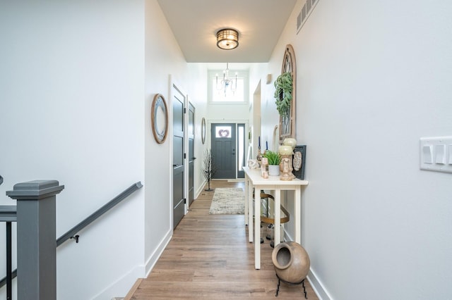 doorway to outside with an inviting chandelier and light hardwood / wood-style flooring