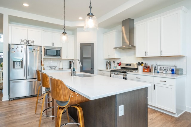 kitchen with wall chimney exhaust hood, appliances with stainless steel finishes, sink, and white cabinets