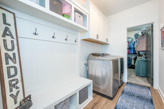 laundry area with cabinets, washer and clothes dryer, and light wood-type flooring