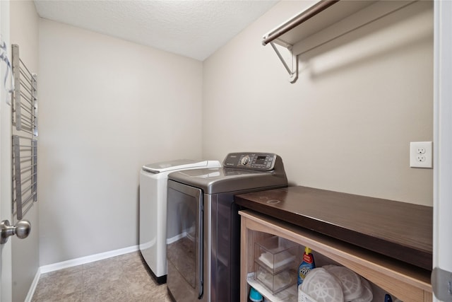 laundry area with light tile patterned floors, a textured ceiling, and washing machine and clothes dryer