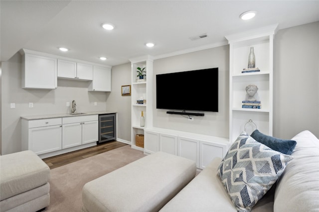 living room featuring wine cooler, crown molding, indoor wet bar, and light wood-type flooring